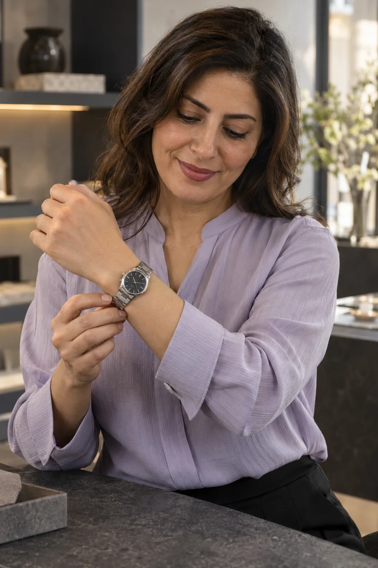 A presenter displays a watch and small accessories in a refined product studio.